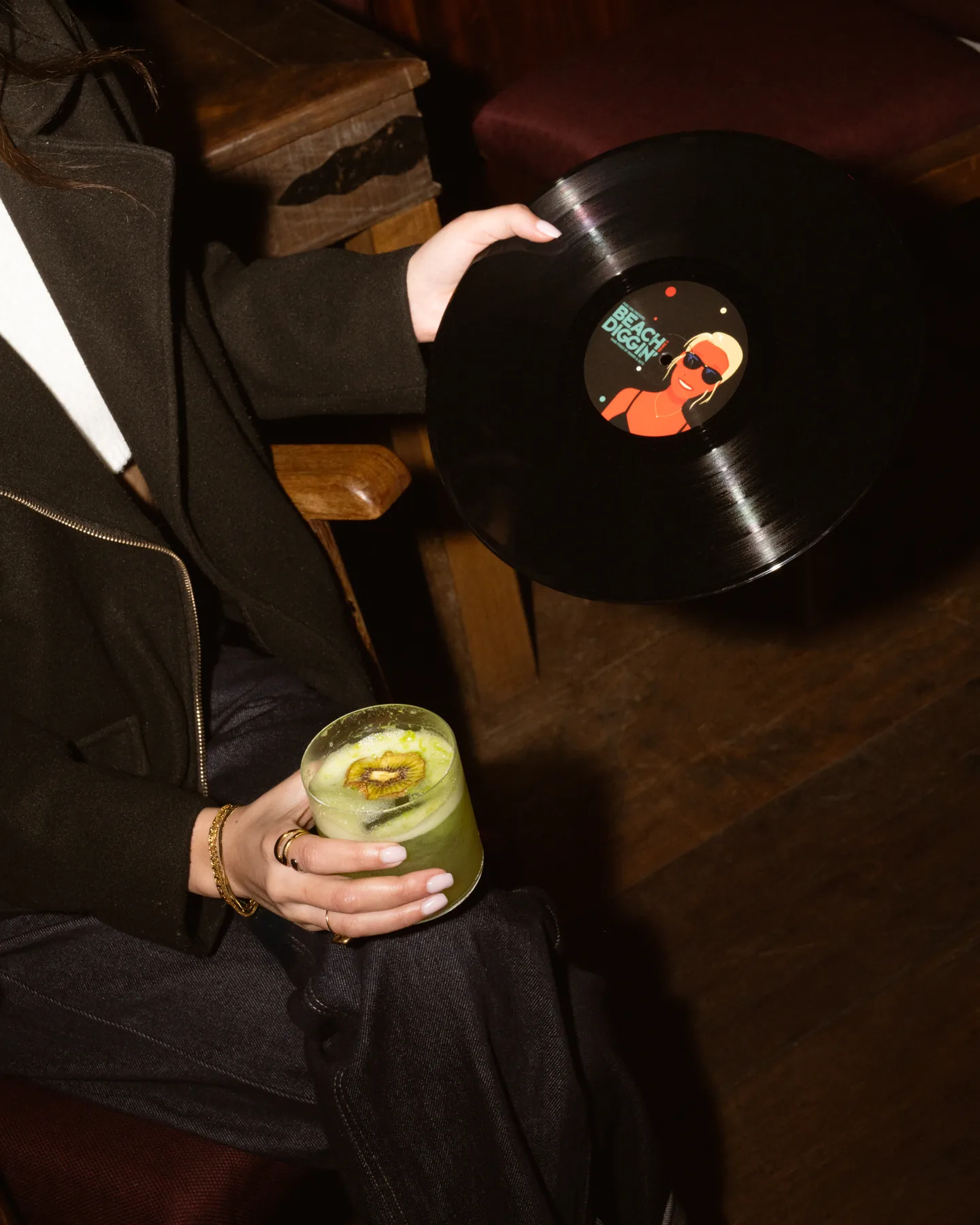 Guest holding a vinyl record and a cocktail at La Cale